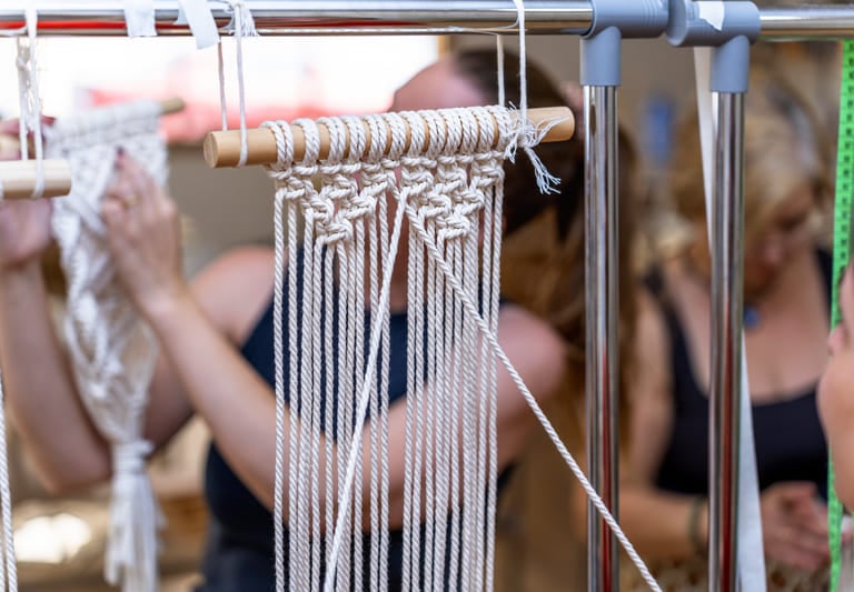 Taller con hilos en color blanco, haciendo una artesanía de macramé