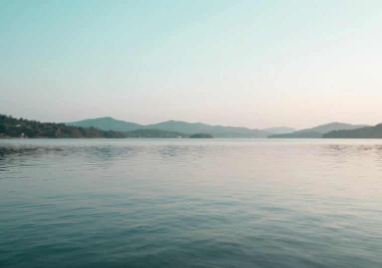 A peaceful landscape with calm waters reflecting a soft sky, utilizing the brand palette of #A7D9D3 and #F8FBFB. Represents mental clarity.