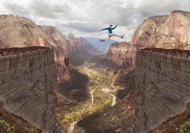 a man jumping over a cliff in the mountains