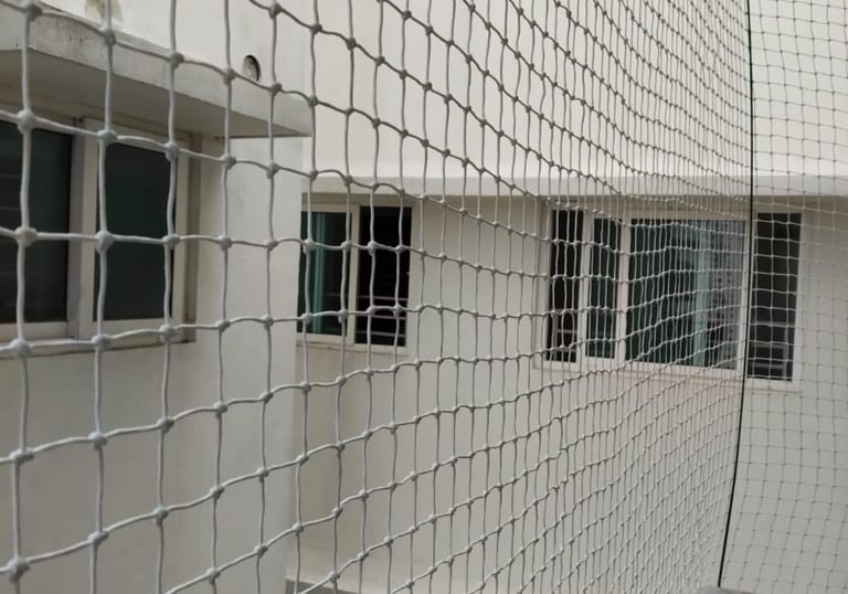 Wide shot of a modern Bengaluru apartment balcony fully covered with neatly fitted pigeon netting by
