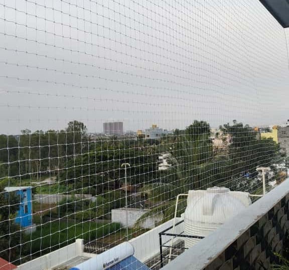 Wide-angle view of a residential building balcony fully covered with a transparent safety net, blend