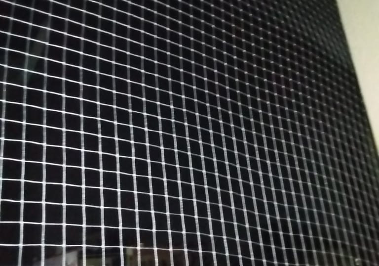 Technician from Arjilli Enterprises carefully fitting a safety net on a Pune apartment balcony.