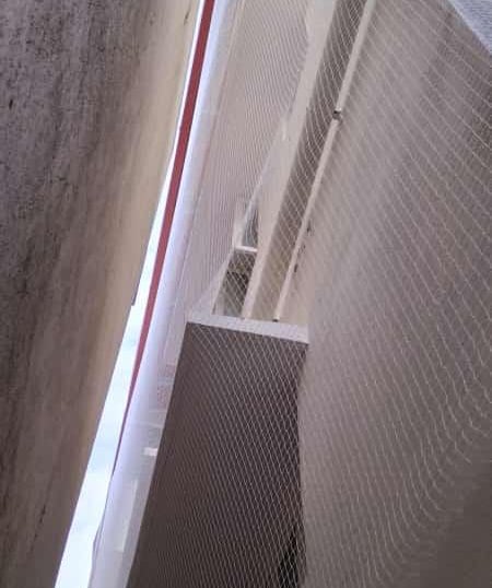 Wide shot showing a balcony fully covered with a durable safety net against a clear sky.