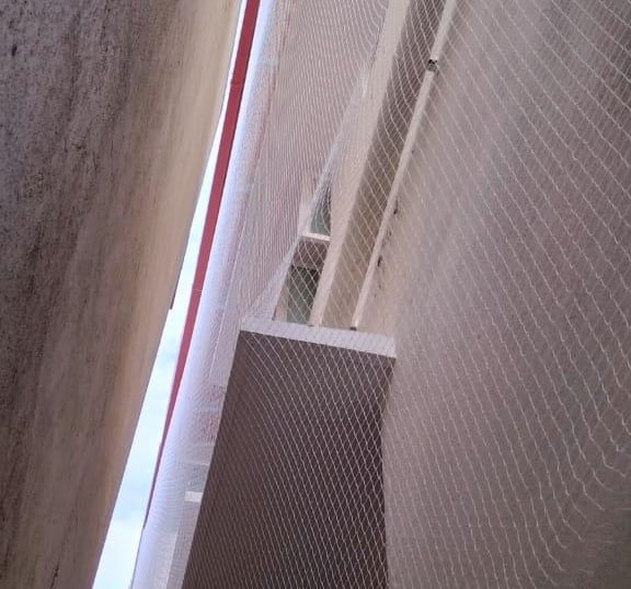 Technician installing a pigeon net on a high-rise apartment balcony.