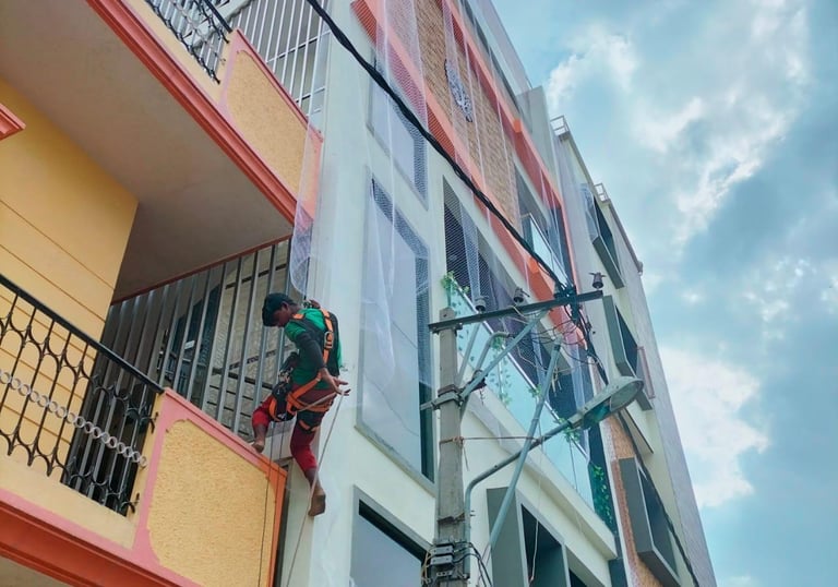 Technician from Arjilli Enterprises carefully installing a balcony safety net, demonstrating attenti