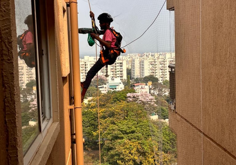 Technician installing a pigeon net on a high-rise apartment balcony in Chennai.