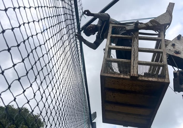 Hands tying knots on durable netting material, showcasing the craftsmanship behind each installation