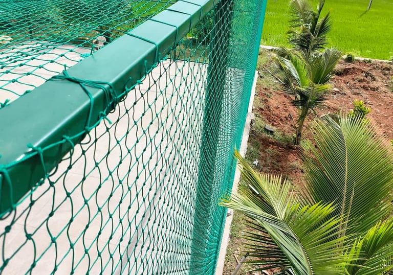 A rooftop cricket net installation with a clear blue sky in Bengaluru.