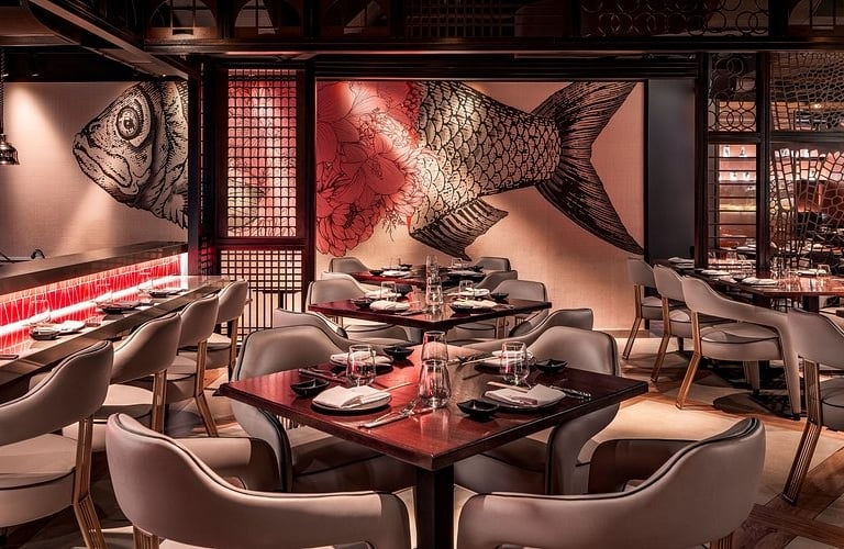 Modern Japanese restaurant interior with wooden tables and a large koi fish wall mural.