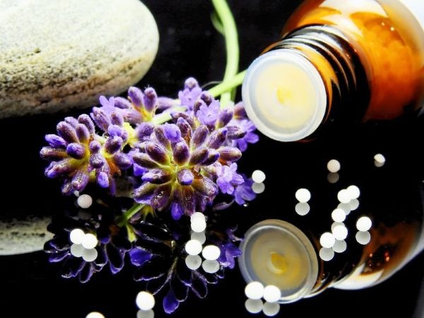 Lavender flowers and homeopathic globules with an essential oil bottle for natural aromatherapy treatment.