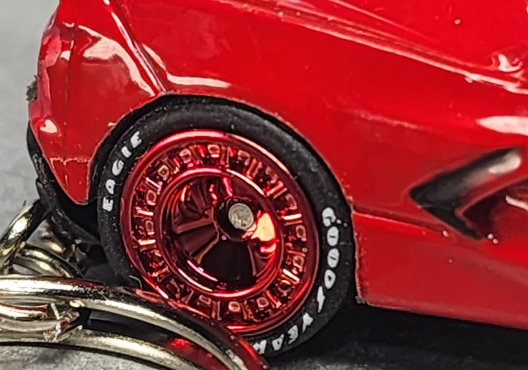 Close-up of a red die-cast toy car with metallic red rims and Goodyear Eagle branded tires.
