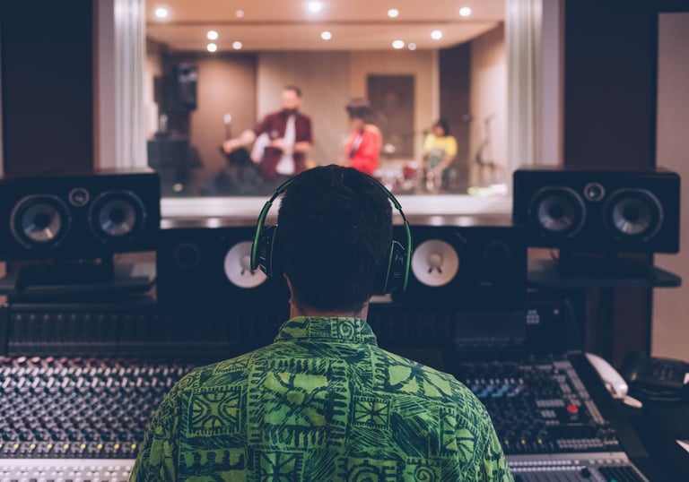 un homme en chemise verte et écouteurs devant un équipement d'enregistrement