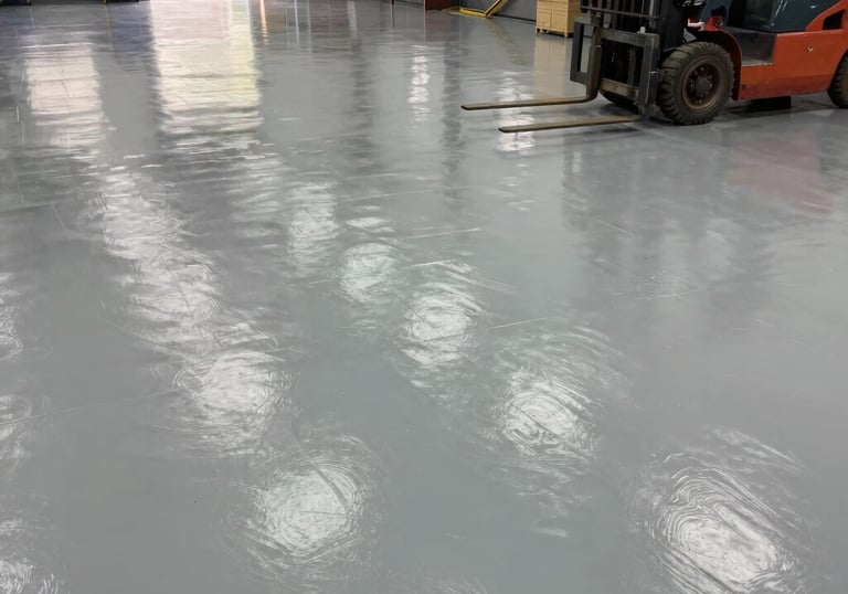 Industrial warehouse floor with sleek, metallic epoxy finish reflecting overhead lights.