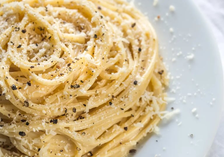 Close-up of creamy cacio e pepe pasta sprinkled with Pecorino Romano cheese and cracked black pepper