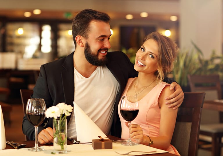 a sugar mommy and her sugar baby sitting at a table with wine glasses