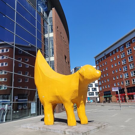 a yellow dog statue of a dog in front of a building