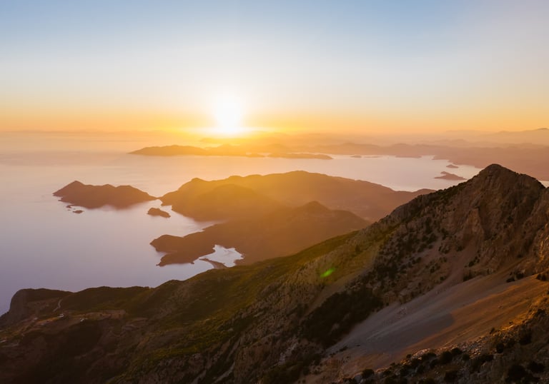 a mountain scene with a sunset over the ocean