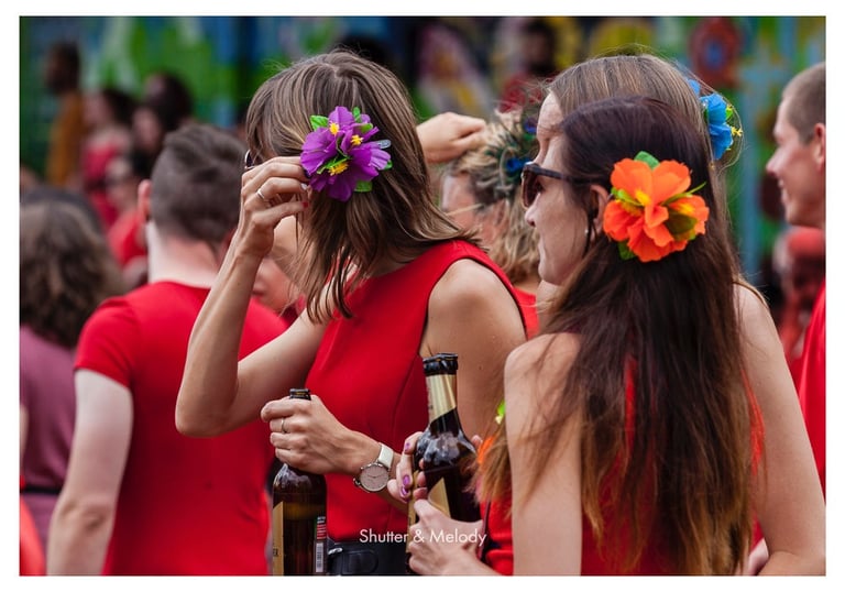 Frauen mit Blumen im Haar in roten Kleidern trinken Bier.