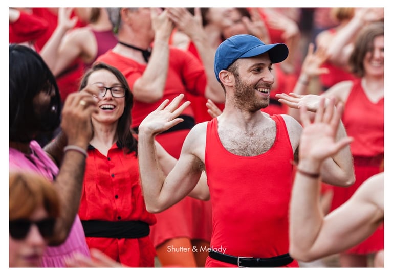 Ein Mann inmitten einer tanzenden Menge, der eine blaue Baseballkappe trägt.