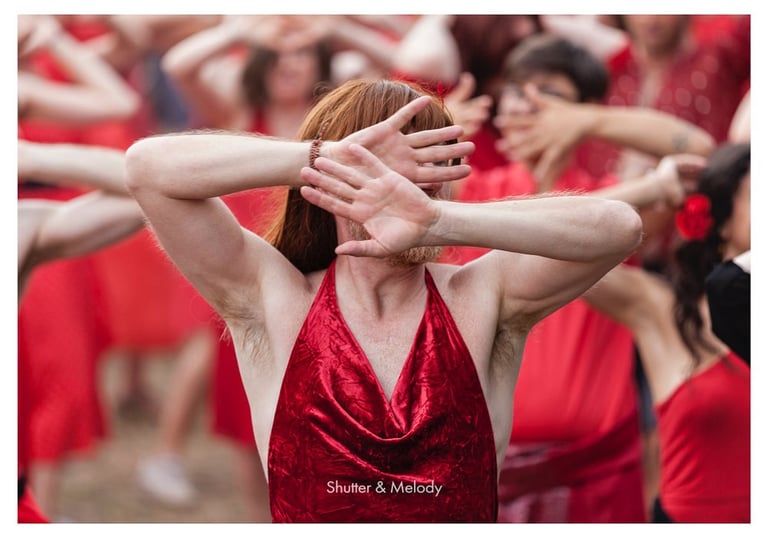 Ein Mann in einem roten Kleid mit roter Perücke tanzt zu einem Lied von Kate Bush.