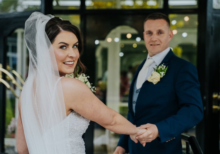 a bride and groom holding hands and smiling