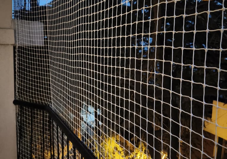 Close-up of a white pigeon net securely installed on a modern apartment balcony in Whitefield.