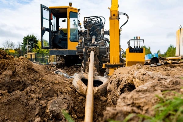 a construction worker is working on a pipe in the ground