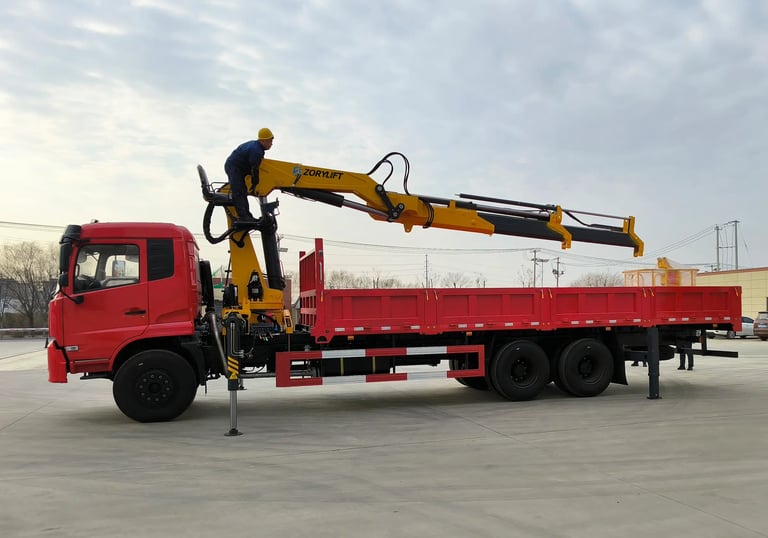 Yellow Zorylift SQZ350A.4 16T knuckle boom crane on red truck operated by worker. Heavy duty, truck/lorry mounted.
