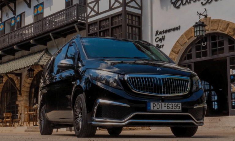 Luxury black Mercedes-Benz V-Class passenger van parked outside a traditional European cafe.