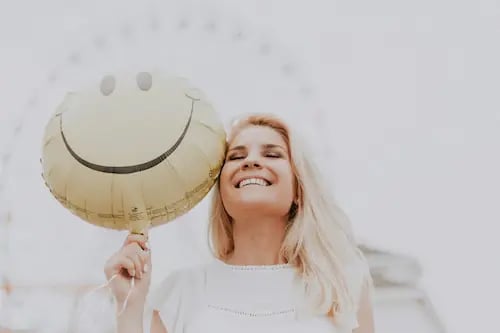 Mulher sorridente segurando um balão de emoji feliz