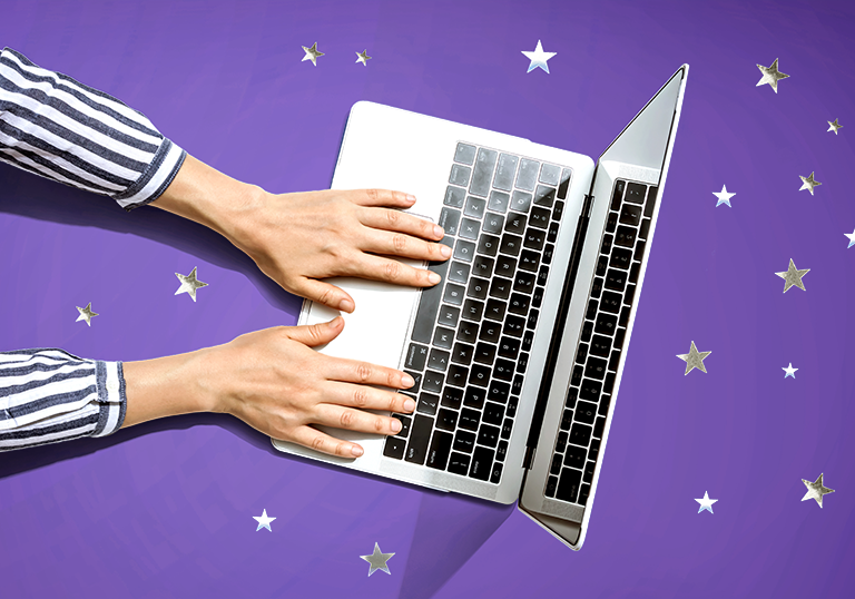 Hands typing on a laptop that is sitting on a purple surface covered in silver stars.