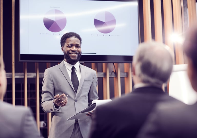 A smiling man in a business suit giving a presentation.