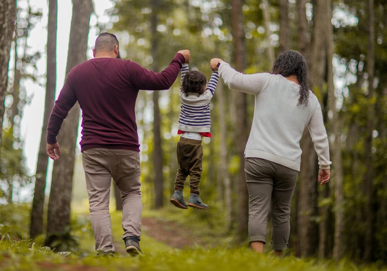 Couple walking through the wood with a young child in between them