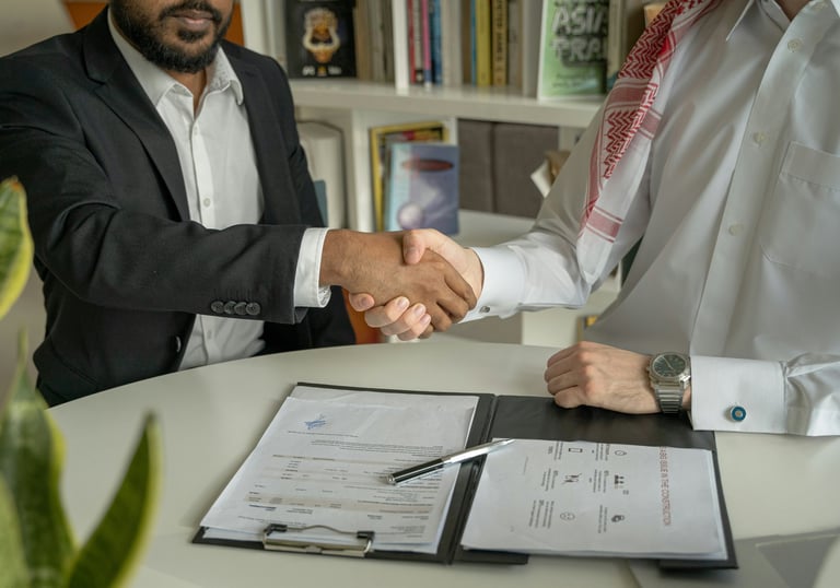 2 people shaking hands over papers