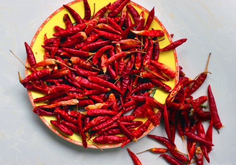 Premium Indian dry red chillies displayed on a yellow plate.