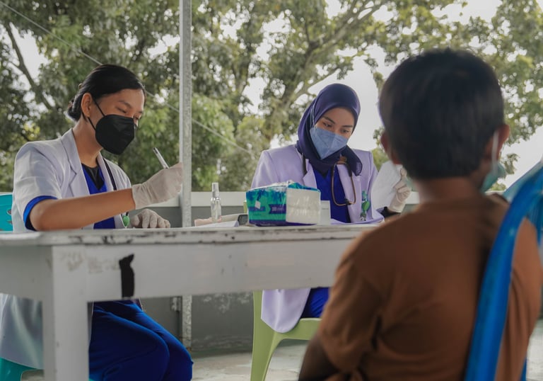 Petugas kesehatan mencatat pemeriksaan pasien di depan puskesmas dalam program pelayanan kesehatan p