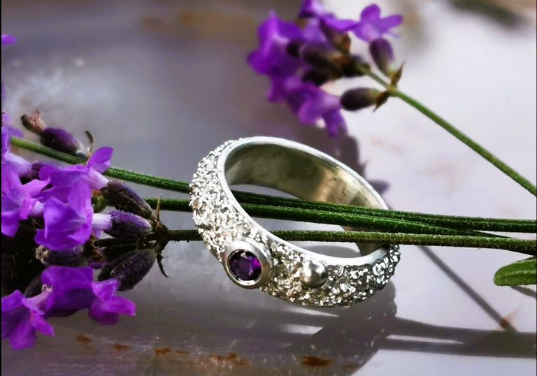 Rankų darbo Viju Jewelry sidabrinis sužadėtuvių žiedas su ametistu, padėtu ant levandų stiebelių.