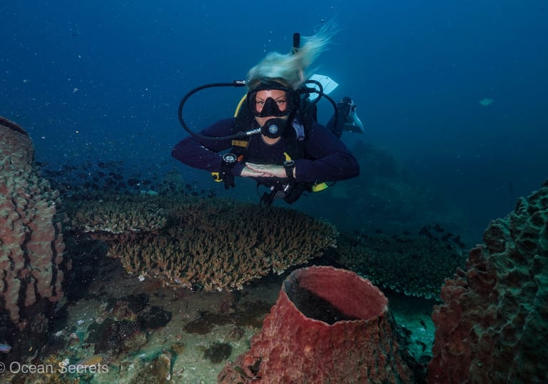 Female scuba diver in perfect horizontal trim hovering over coral reef during a PADI Deep Diver cour