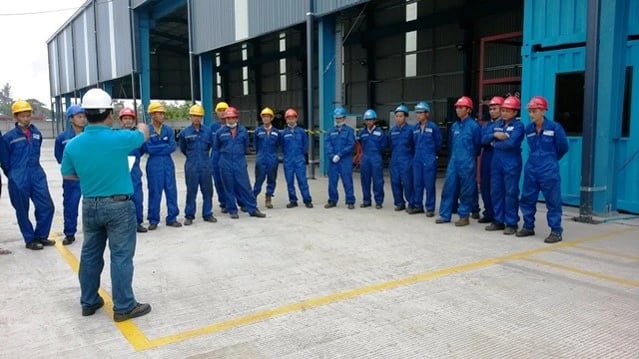 Industrial workers and hard hats attend a safety briefing at a warehouse.