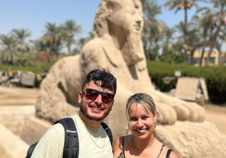 Casal de turistas visitando a Esfinge de mármore em Mênfis (Egito) durante passeio histórico no Egito