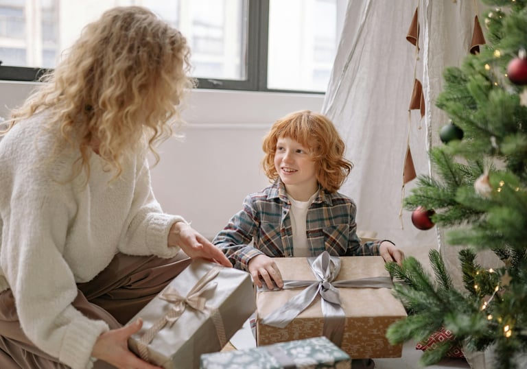 Mother giving her daughter a gift under Christmas tree
