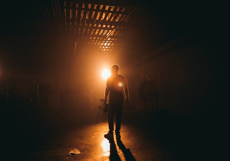 a man standing in a dark room with a light shining on his face