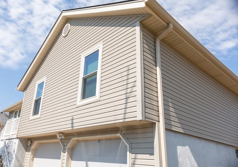 a house showing tan siding, white framed windows and tan gutters