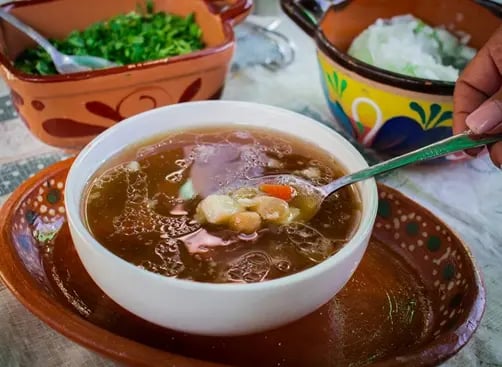 Consomé tradicional de barbacoa con garbanzos servido en plato artesanal en Querétaro.