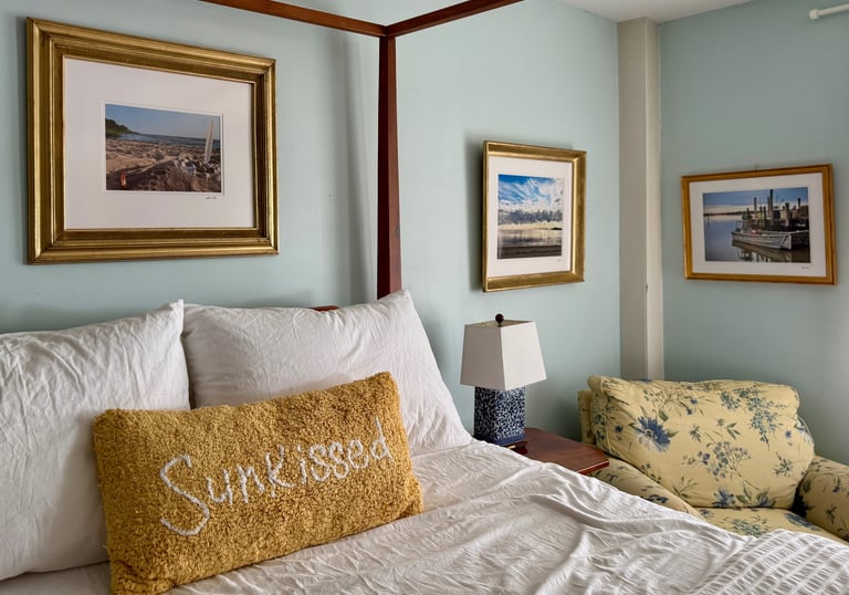Ensuite bedroom with 4-poster bed, water views, and original framed artwork.