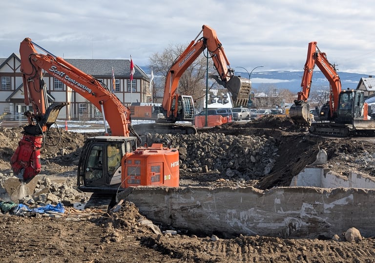 three excavators demolishing a commercial structure