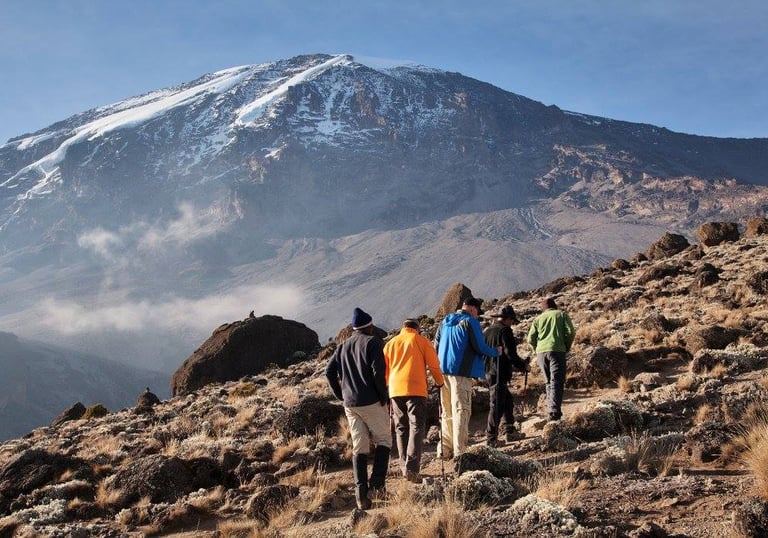 People hiking Kilimanjaro, with background of the mountain from a distance