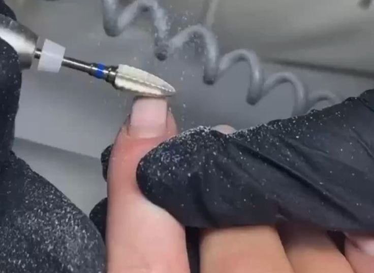 a person is using a needle tip to get a manicured nail