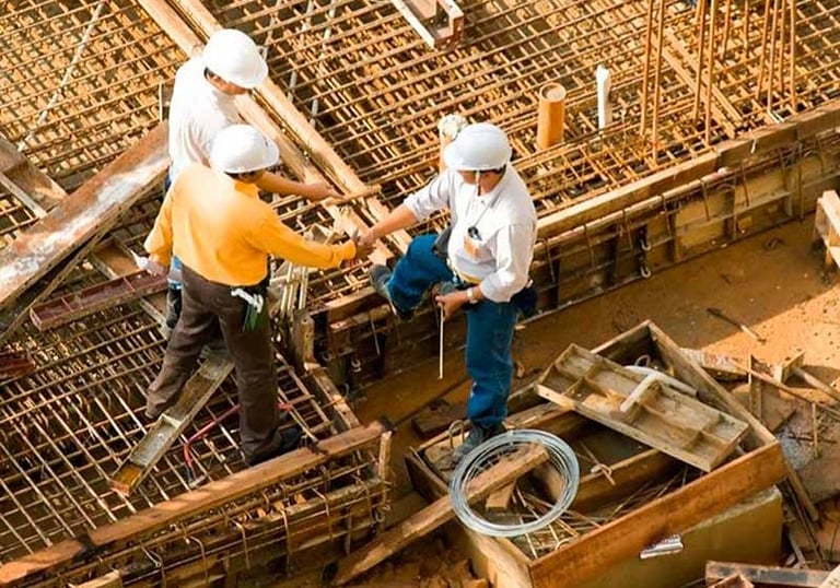 Ingenieros y técnicos revisando planos sobre estructura en obra, simbolizando asesoría y consultoría