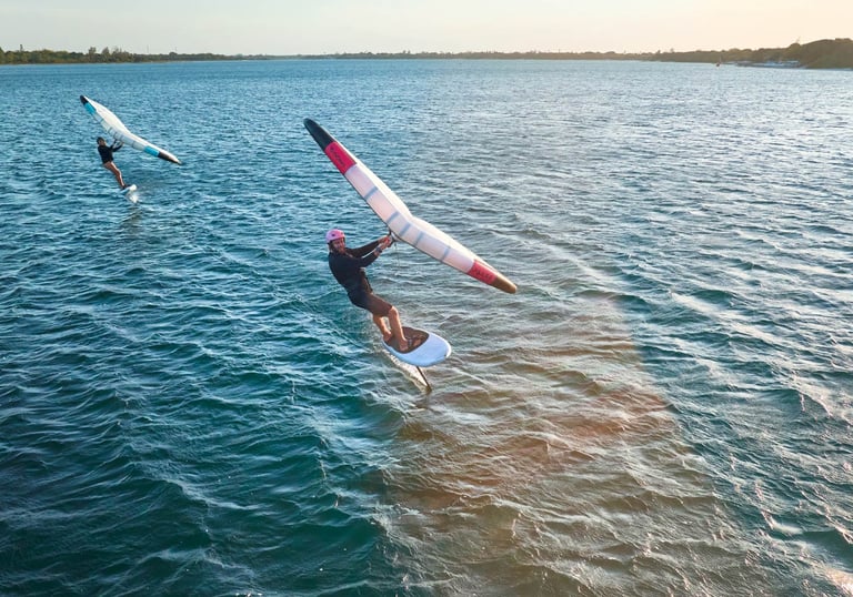 Saulėlydis Svencelėje su wing foil sportininku virš vandens paviršiaus